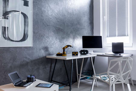 Contemporary study room in grey with simple desk, crystal chair and computer