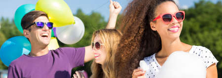 Young man with baloons standing behind two women with the candyflossの写真素材