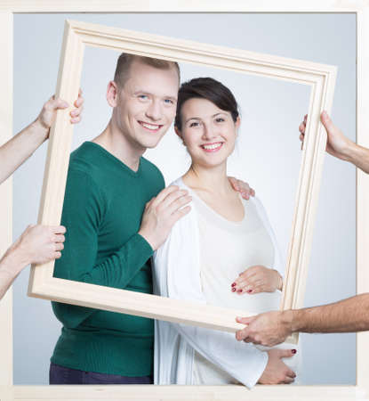 Shot of a future young parents in a frame holded by somebody's handsの写真素材