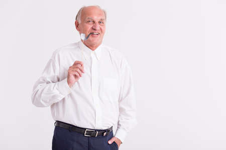 Shot of a senior man holding a paper pipe on a stick while looking at a camera