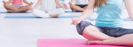 Close up of a woman sitting on a floor and meditating during yoga classes, panoramaの写真素材