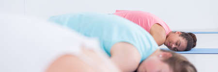 Close up of a women lying on a floor in a stretch pose during yoga classes, panorama