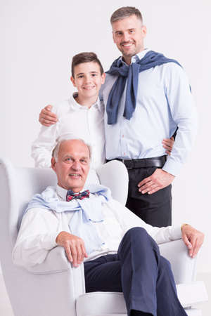 Shot of an elderly gentleman sitting in the armchair while his son and grandson standing behind him