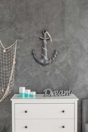 Anchor decor hanging on the wall above the white commode