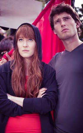 Pessimistic couple participating in a protest, standing before a red flagの写真素材