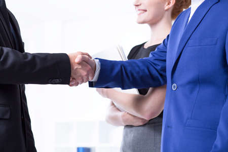 Close up of a business handshake, businesswoman in the backgroundの写真素材