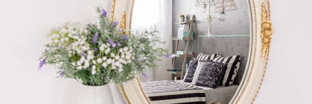 Mirror reflection of a stylish bedroom with the comfortable bedの写真素材