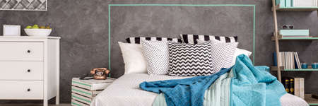 Various theme pillows lying on a marital bed close to the white commodeの写真素材