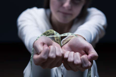 Closer shot of woman's hands tied by a centimeterの写真素材
