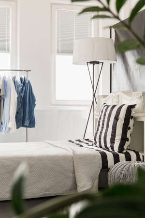 Modern design light flat with window, clothes rack, bed and floor lampの写真素材