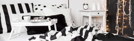 Closeup shot of a white breakfast tray standing on a bedの写真素材