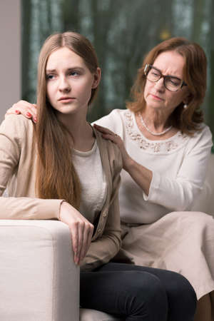 Woman therapist sitting on a couch behind the young teenagerの写真素材