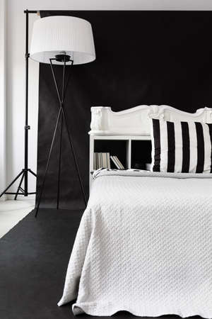 Black and white photographer studio interior with white bed and floor lamp