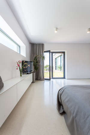 Terrace window in bright minimalist bedroom with grey textilesの写真素材
