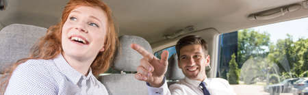 Young couple sitting in a car with the man pointing something by his finger