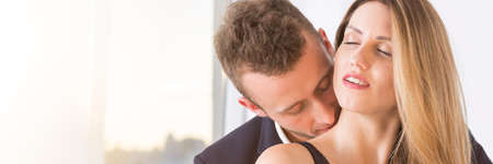Handsome businessman kissing young woman at his office, panorama