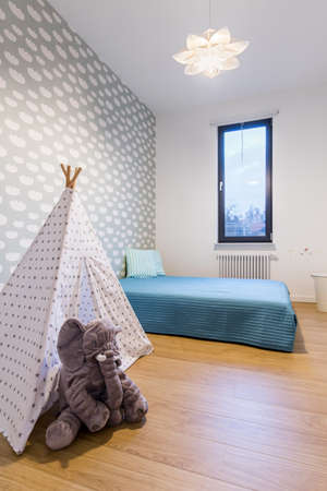Child room with a bed, toy tent and funny shaped lamp
