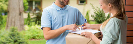 Young woman signing a delivery confirmation in front of her house