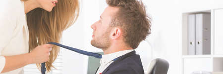 Sexy businesswoman holding handsome man's tie, panoramaの写真素材