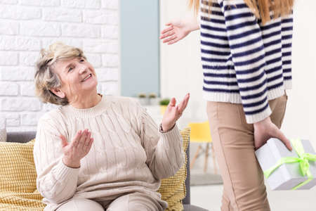 Granddaughter giving a birthday present to a surprised grandmaの写真素材