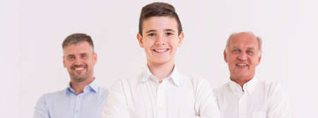Small boy standing with his father and grandfather on a white background, panoramaの写真素材