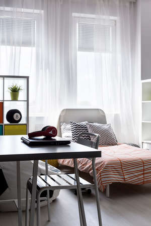 Minimalistic desk in bright bedroom with the cosy bed behindの写真素材