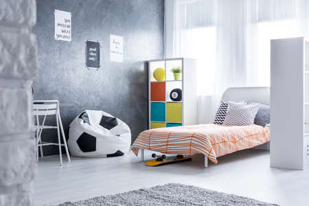 Bedroom of teenager with comfortable bed, rack and bean bag chairの写真素材