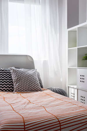 Comfortable bed with cushions and the window curtain behindの写真素材