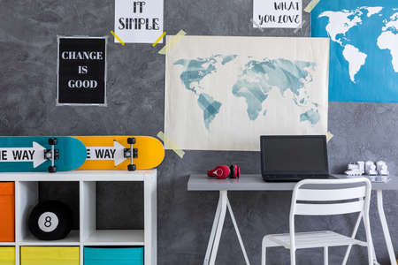 Skateboards located on a commode close to the desk and wall with maps