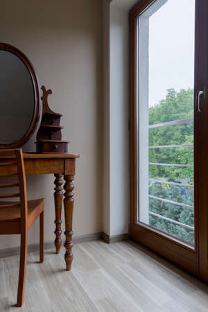 Room corner with parquet, wooden chair, elegant dressing table with a mirror and the window with the view of a gardenの写真素材