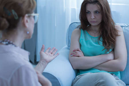 Doctor in glasses cheering sad female patientの写真素材
