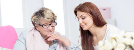 Shot of senior woman in glasses with her granddaughter sitting close each otherの写真素材