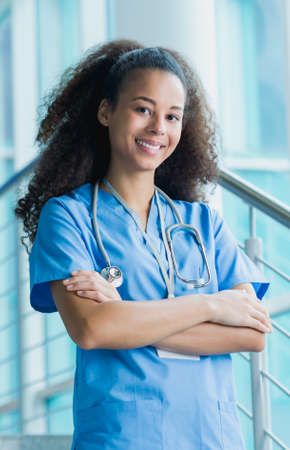 Portrait of a female medical intern in a blue uniform, smiling