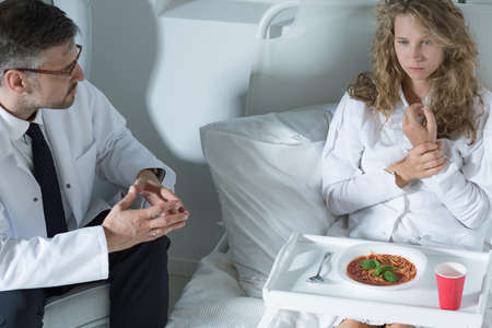 Shot of a doctor trying to convince his patient to eat a soupの写真素材