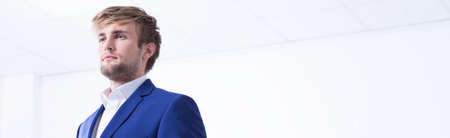 Young confident businessman in a suit is standing lost in thoughtの写真素材