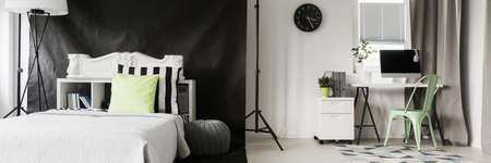 Modern flat with bed and  minimalistic desk and chair located close to the windowの写真素材