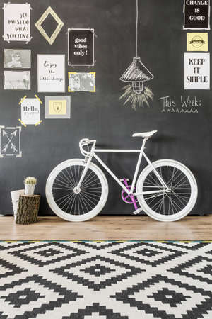 Shot of a white bike against a blackboard wall with postersの写真素材