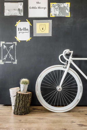Shot of a white bike standing against a chalkboard wall decorated with posters and photos
