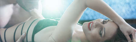 Woman in sexy lace lingerie is lying on a bed while man is touching her bodyの写真素材