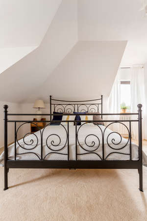 Light bedroom with large bed with decorative metal footboardの写真素材