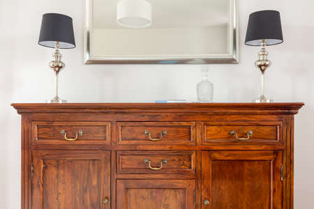Stylish wooden dresser, two small lamps and mirror in a modern frameの写真素材