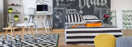 Room of a teenager with bed, minimalistic furniture and guitarの写真素材