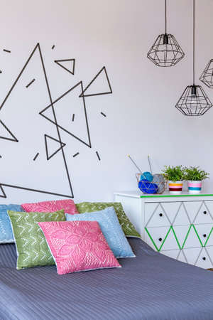 Cropped shot of a double bed with colorful pillows and grey bedcover
