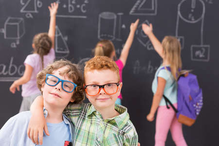 Shot of two little boys standing in front of a chalkboard wallの写真素材