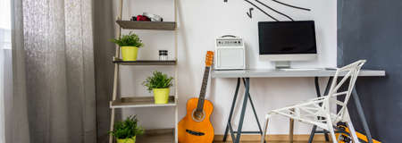Home office area with minimalistic desk, chair, rack and the guitarの写真素材