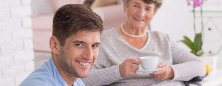 Shot of a handsome caregiver sitting close the smiled senior womanの写真素材