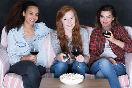 Shot of three young woman sitting on a sofa and watching a movieの写真素材