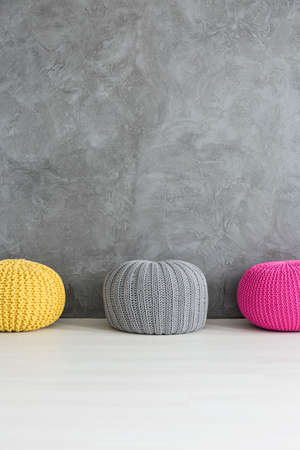 Three color poufs standing beside grey wall with decorative finishの写真素材