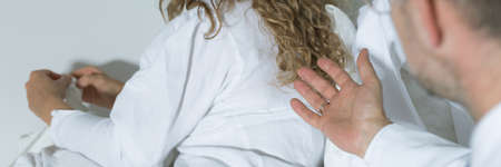 Psychotherapist trying to make a conversation with his patient sitting back to himの写真素材