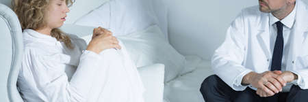 Shizophrenic woman sitting on an armchair and talking with her psychotherapistの写真素材